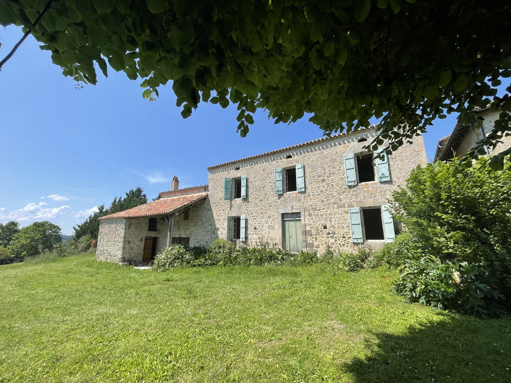 Maison gasconne en pierre située au bord d’un hameau avec des vues lointaines sur la campagne environnante